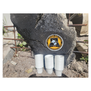 “Cafecito cups with Search Grounds logo in a rubble pile, highlighting the brand’s connection to resilience and tough environments.”