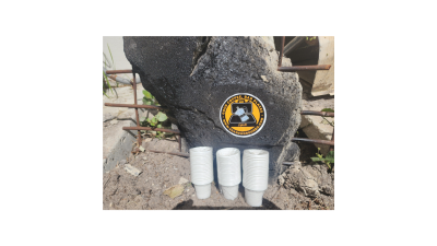 “Cafecito cups with Search Grounds logo in a rubble pile, highlighting the brand’s connection to resilience and tough environments.”